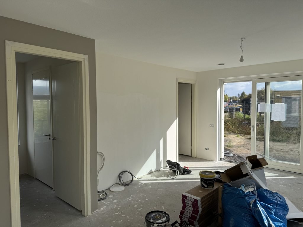 Nieuwbouwwoning met afgewerkte wanden, verfemmers en tuindeuren naar een bouwterrein