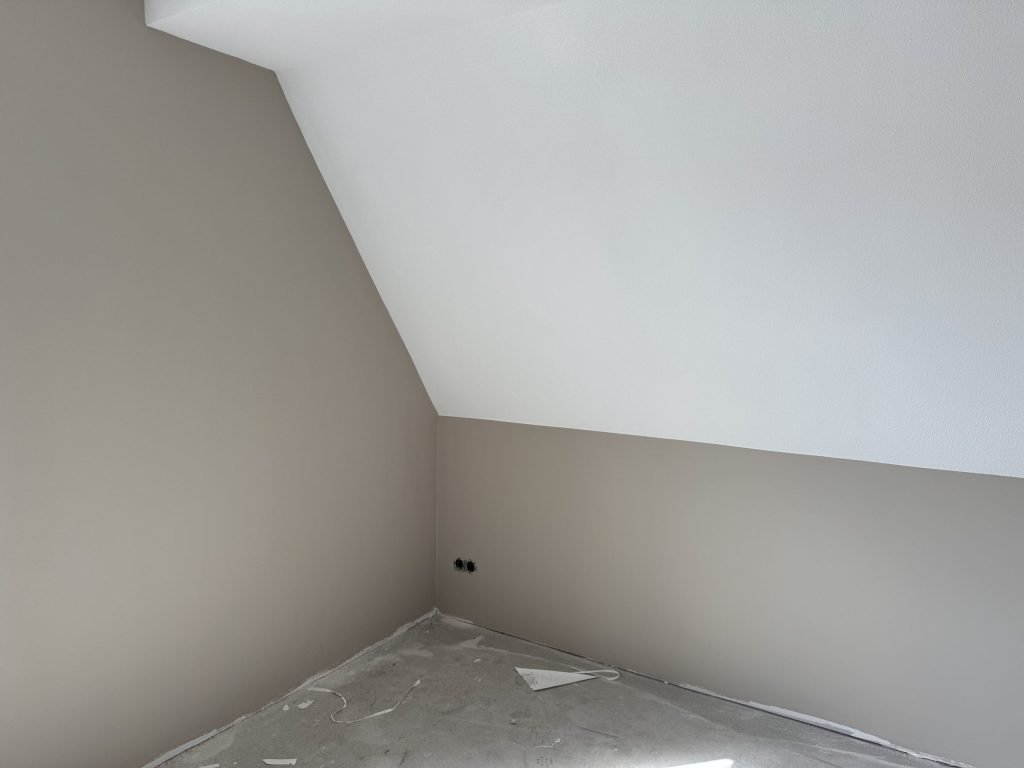 Zolderkamer met schuine wand, de muren in een warme grijstint en het schuine vlak wit