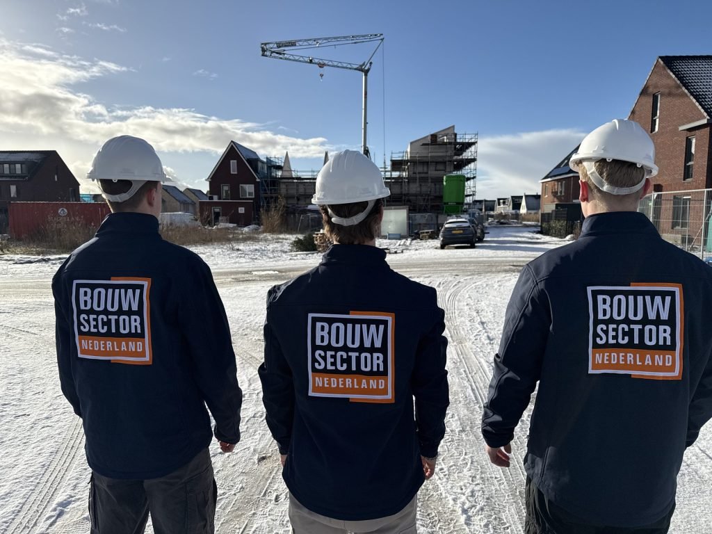 Drie vakmensen van Bouwsector Nederland met witte helm op een nieuwbouwlocatie in de sneeuw
